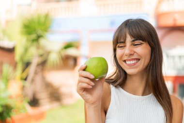 Genç bir kadın elmalı ve mutlu.