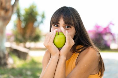 Dışarıda elinde elma tutan genç bir kadın.