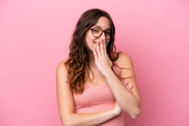 Pembe arka planda izole edilmiş genç beyaz kadın mutlu ve gülümsüyor.