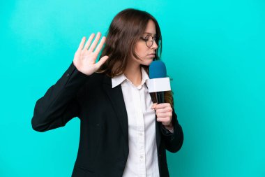 Genç TV sunucusu, mavi arka planda izole edilmiş bir kadın dur hareketi yapıyor ve hayal kırıklığına uğruyor.