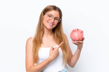 Genç, sarışın bir kadın kumbarayı beyaz arka planda izole edip ona doğrultuyor.