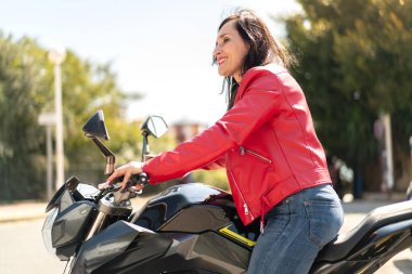 Açık havada motosikletli orta yaşlı bir kadın.