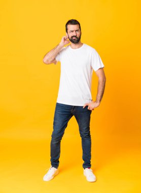 İzole edilmiş sarı arka planda sakallı bir adamın tam boy fotoğrafı. Şüpheleri var.