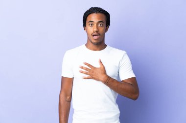 Örgülü genç Afrikalı Amerikalı adam mor arka planda izole edilmiş sağa bakarken şaşırmış ve şok olmuştu.