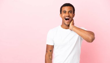 Telif uzayındaki Afro-Amerikalı adam. Pembe arka plan. Şaşırmış ve şok olmuş yüz ifadesi var.