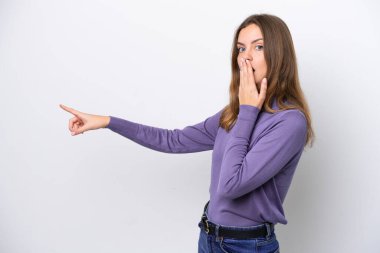 Beyaz arka planda izole edilmiş beyaz tenli genç bir kadın sürpriz bir ifadeyle işaret ederken...