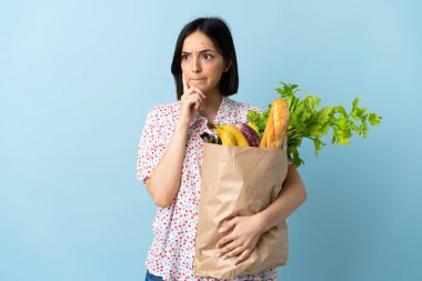 Elinde alışveriş çantası tutan genç bir kadın. Şüpheleri ve düşünceleri var.