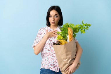 Market poşeti tutan genç bir kadın sağa bakarken şaşırmış ve şok olmuştu.