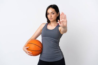 Beyaz arka planda basketbol oynayan genç bir kadın dur hareketi yapıyor.