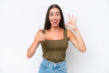 Beyaz arka planda izole edilmiş genç beyaz bir kadın tamam işareti ve baş parmak hareketi gösteriyor.