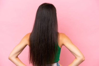 Genç beyaz kadın pembe arka planda izole edilmiş arka planda ve yan bakıyor.