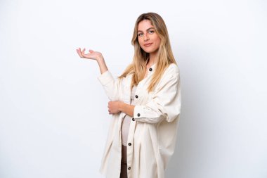Genç Uruguaylı kadın, beyaz arka planda izole edilmiş, davet edilmek için ellerini yana uzatıyor.