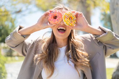 Genç, güzel sarışın Uruguaylı kadın açık havada elinde donutlarla.