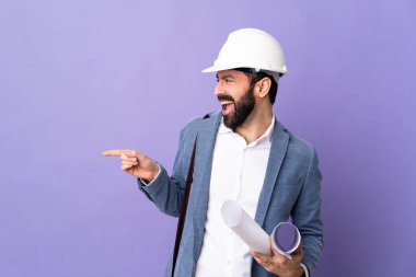 Miğferli genç bir mimar, izole edilmiş mor arka plan üzerinde planları var.