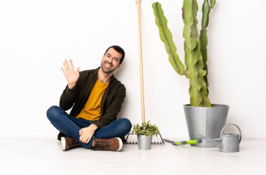 Bahçıvan içeride yerde oturmuş, mutlu bir ifadeyle selamlıyor.