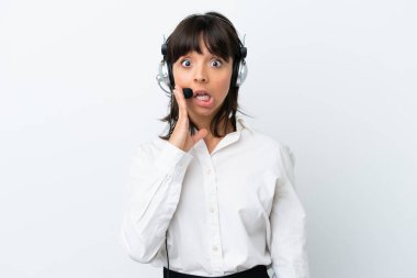 Tele pazarlamacı melez kadın beyaz arka planda izole edilmiş bir kulaklıkla çalışıyor. Şaşırmış ve şok olmuş bir yüz ifadesi var.