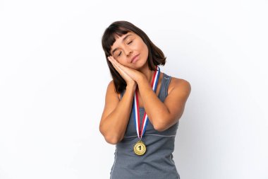 Beyaz arka planda madalyaları olan genç melez bir kadın uyku jesti yapıyor.