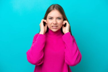 Genç Litvanyalı kadın mavi arka planda izole edilmiş hayal kırıklığına uğramış ve kulaklarını kapatmış