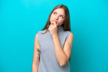 Genç Litvanyalı kadın mavi arka planda izole edilmiş. Şüpheleri var.