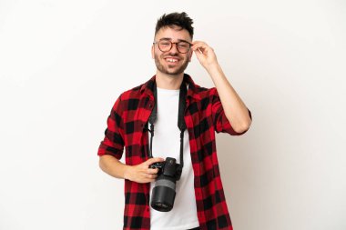 Genç fotoğrafçı beyaz arka planda gözlüklü ve mutlu.