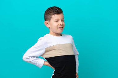 Küçük çocuk mavi arka planda izole edilmiş. Çaba sarf ettiği için sırt ağrısı çekiyor.