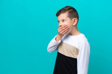 Küçük çocuk mavi arka planda izole edilmiş. Yan tarafa bakarken sürpriz jest yapıyor.