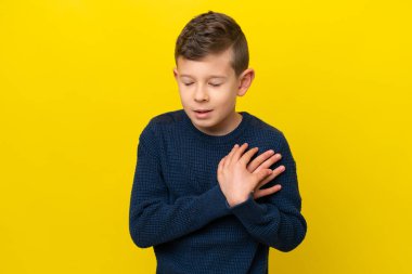 Sarı arka planda izole edilmiş küçük beyaz çocuk. Kalbinde bir ağrı var.