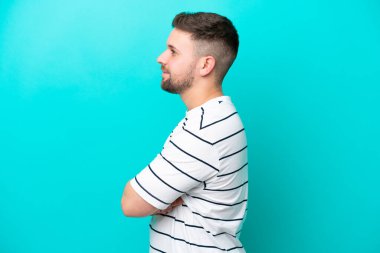 Kafkasyalı genç adam mavi arka planda yan pozisyonda izole edildi.