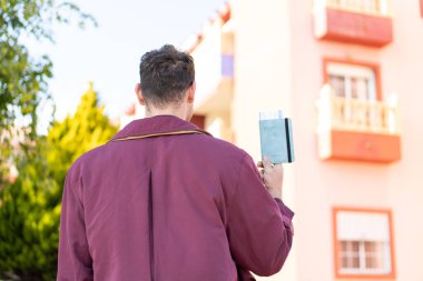 Arka tarafta elinde pasaport tutan genç beyaz bir adam var.