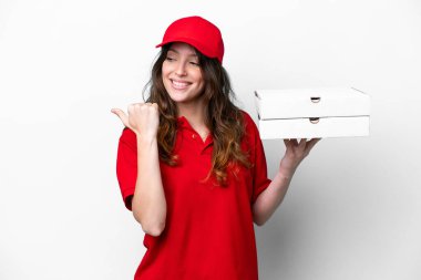 İş üniformalı bir pizzacı kadın beyaz arka planda izole edilmiş pizza kutularını topluyor ve bir ürün sunmak için yan tarafa bakıyor.
