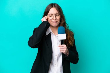 Genç TV sunucusu, mavi arka planda izole edilmiş, hayal kırıklığına uğramış ve kulaklarını kapatmış bir kadın.