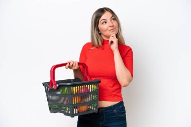 Genç Romen kadın elinde yiyecek dolu bir sepet tutuyor beyaz arka planda izole edilmiş ve yukarı bakıyor