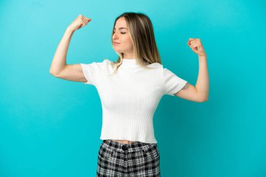 Soyutlanmış mavi arka planı olan genç bir kadın güçlü bir jest yapıyor.