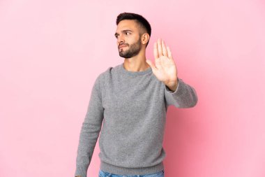 Pembe arka planda izole edilmiş genç beyaz adam dur hareketi yapıyor ve hayal kırıklığına uğruyor.