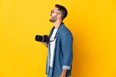 Sarı arka planda izole edilmiş genç fotoğrafçı kız yan yana gülüyor.