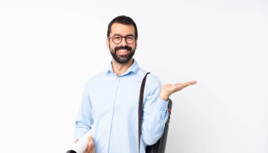 Young architect man with beard over isolated white background holding copyspace imaginary on the palm to insert an ad