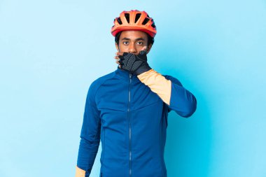 Saçları örülmüş, ağzı elle kapatılmış genç bir bisikletçi.