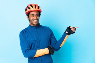 Young cyclist man with braids over isolated background pointing finger to the side clipart