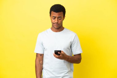 Sarı arka planda yaşayan Afro-Amerikalı yakışıklı bir adam düşünüyor ve mesaj gönderiyor.