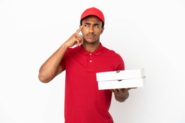 Afro-Amerikalı pizza teslimatçısı izole edilmiş beyaz duvarın üzerinden pizza kutuları alıyor. Şüpheleri var ve düşünüyor.