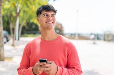Dışarda cep telefonu kullanan genç bir İspanyol.