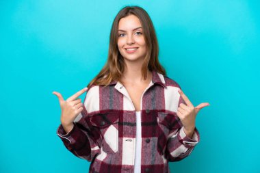 Mavi arka planda izole edilmiş beyaz bir kadın baş parmak işareti yapıyor.