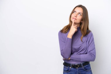 Beyaz arka planda izole edilmiş genç beyaz kadın yukarı bakarken şüpheleri var.