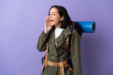 Arka planda geniş bir sırt çantası olan genç dağcı kadın ağzı sonuna kadar açık bağırıyor.