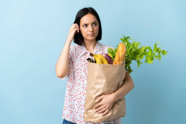 Elinde alışveriş çantası tutan genç bir kadın. Şüpheleri ve düşünceleri var.