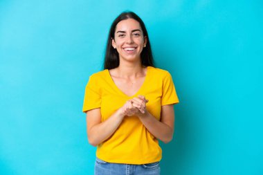 Mavi arka planda izole edilmiş genç beyaz kadın gülüyor.