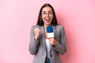 Pembe arka planda izole edilmiş beyaz televizyon sunucusu kadın zaferi kutluyor.