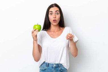 Beyaz arka planda izole edilmiş genç beyaz kadın şaşırmış ve ön tarafı işaret ediyor.