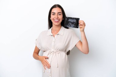 Beyaz arka planda izole edilmiş genç beyaz kadın hamile ve ultrason çekiyor.
