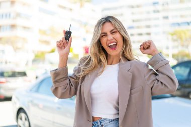 Sarışın, güzel Uruguaylı kadın arabanın anahtarlarını tutuyor ve zaferi kutluyor.